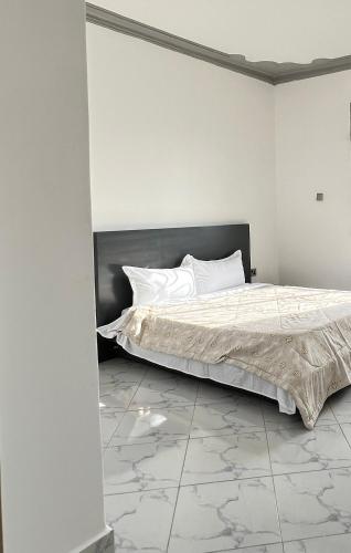 a white bedroom with a bed with white pillows at Dutus Hotel Entebbe in Wakiso