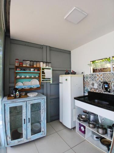 a small kitchen with a white refrigerator and a counter at Casa Contêiner imersão com Natureza Floresta Sapiranga-5km praia do forte in Mata de Sao Joao