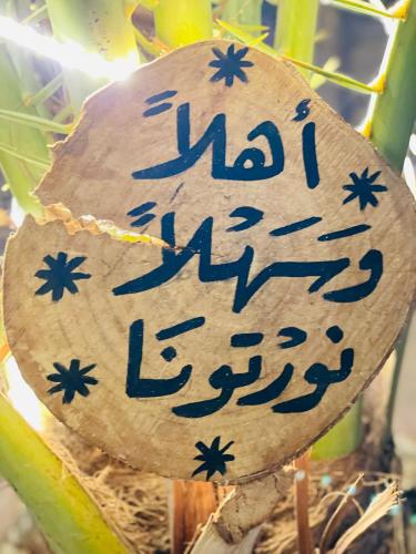 a sign on a piece of wood with writing on it at Shasha Ecolodge in Siwa