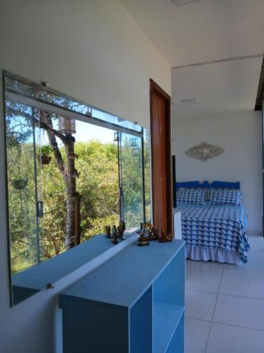 a bedroom with a bed and a large glass window at Casa Contêiner imersão com Natureza Floresta Sapiranga-5km praia do forte in Mata de Sao Joao