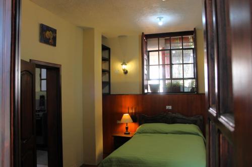 a bedroom with a green bed and a window at Apart Hotel Loma Chica Quito in Quito