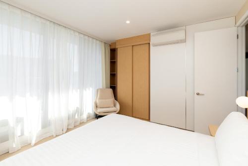 a bedroom with a white bed and a chair at Maxim Hotel - Auckland in Auckland