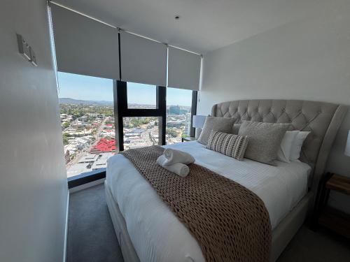 布里斯班Luxury Peppers Infinity Pool Stylish with 2BD & 1C Park的一间带大床和大窗户的卧室
