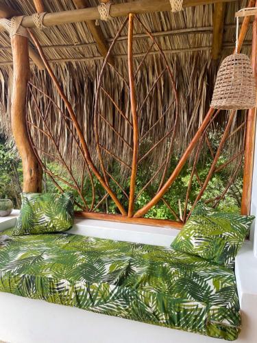 a bench with green cushions and a straw roof at Kamajorú Ecohabitat in Tubará