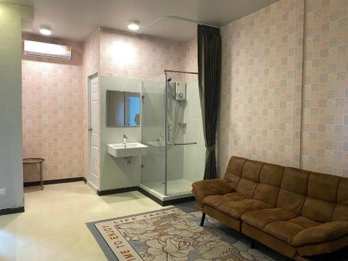a living room with a couch and a shower and a sink at Duck House Hostel & Resort Khon Kaen in Ban Pet