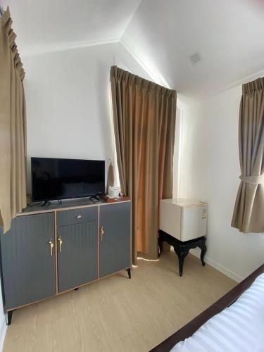 a bedroom with a tv on a dresser with a bed at Duck House Hostel & Resort Khon Kaen in Ban Pet