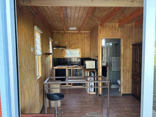a kitchen with wooden walls and a table and a stove at Cabañas Rivera Del Ancoa in Linares