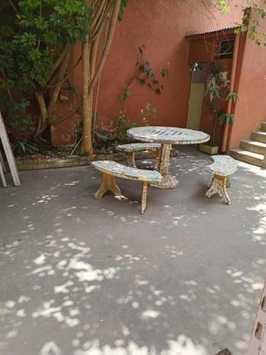 two benches and a table in front of a building at Habitaciones en Casa Céntrica cerca de todo in Colonia del Sacramento