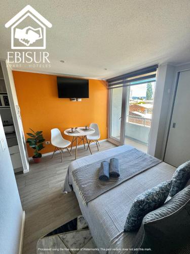 a bedroom with a bed and a table with chairs at EBISUR Apart - Hoteles CRUZ in Concepción