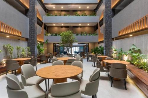 Un vestíbulo con mesas, sillas y plantas. en Beach Haus - Flat Luxo Automatizado 538, en João Pessoa
