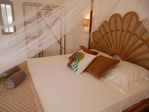 a white bed with a wooden headboard in a room at Coco Soley in Le Diamant