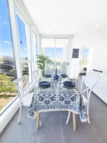 a dining room with a table and chairs and windows at Olympic Park Escape 2BR w Gym, Pool & Free Parking in Sydney