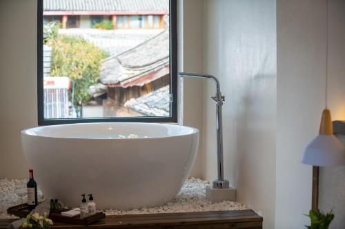 a white bath tub in a bathroom with a window at 清舍雪山观景设计师民宿 in Lijiang