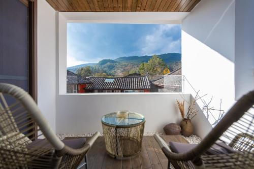a balcony with chairs and a window with a view at 清舍雪山观景设计师民宿 in Lijiang