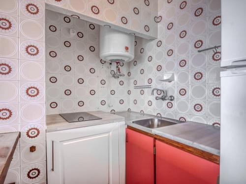 a small kitchen with a sink and red cabinets at Beachfront Apartment in Platja Almadrava in Montjoys