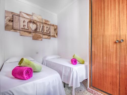 two beds in a room with pink and green pillows at Beachfront Apartment in Platja Almadrava in Montjoys