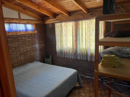 a bedroom with a bed in a room with windows at Cabañas Terraza Sur in El Bolsón