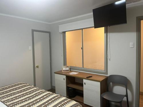 a bedroom with a desk with a bed and a window at Alternativo Hostales in Caldera
