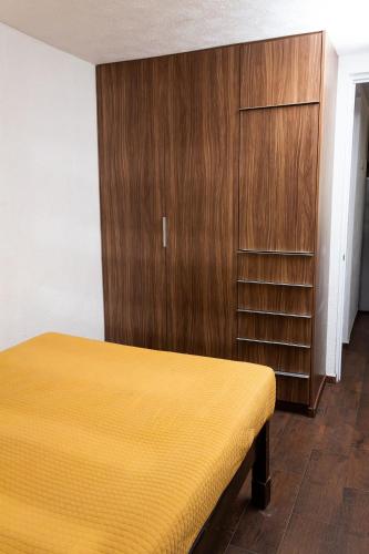 a bedroom with a bed and a wooden cabinet at Departamento cerca de Zoológico y Estadio Jalisco in Guadalajara