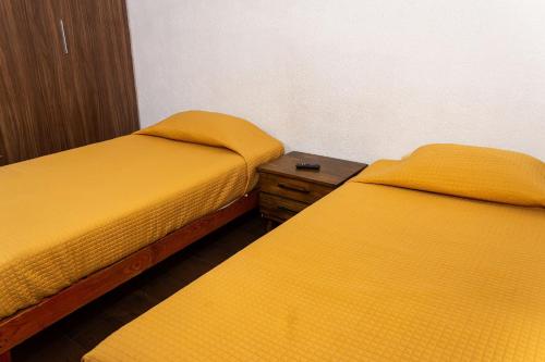 two beds in a room with yellow sheets at Departamento cerca de Zoológico y Estadio Jalisco in Guadalajara