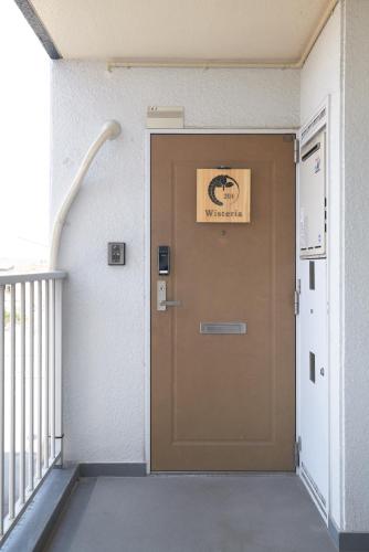a brown door in a building with a sign on it at Westeria201 ペット子供歓迎JR春日井駅より徒歩3分長期滞在に最適 in Kasugai