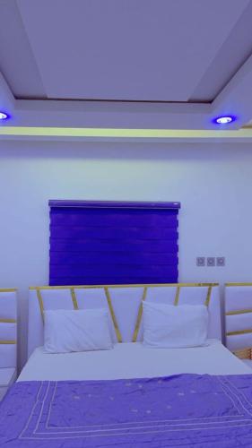 a bedroom with a bed with a blue board above it at Urban Shortlet Abuja in Abuja