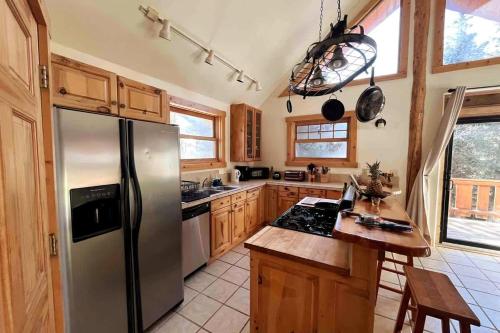 a kitchen with a stainless steel refrigerator and wooden cabinets at Cabin-Style Ski Home in Minturn with Private Deck in Minturn