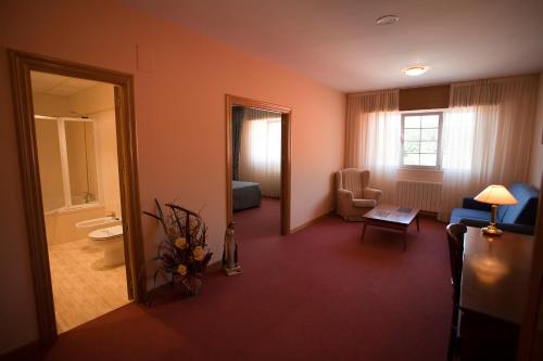 Habitación con sala de estar con sofá y silla. en Hotel Restaurante La Alhama, en Medina de Pomar