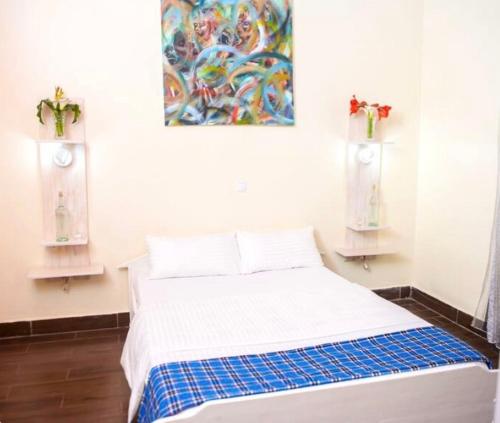 a bed in a room with a painting on the wall at Little Birds Paradise in Ruhengeri