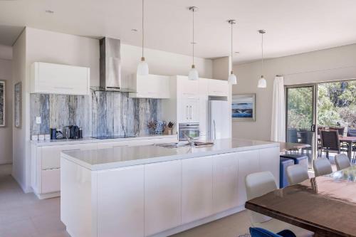 a kitchen with white cabinets and a dining room at Panorama in Dunsborough