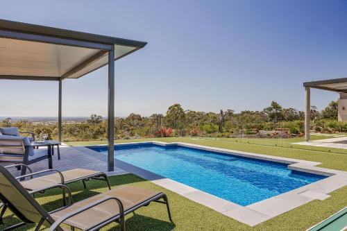 a swimming pool in a house with chairs and a patio at Panorama in Dunsborough