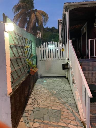 a walkway leading to a house with a fence and a palm tree at MAISON FAMILLE RANCE in Pointe-Noire