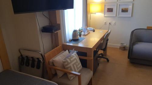 a room with a desk with chairs and a television at Flat Hotel Aeroporto Congonhas com piscina (110H) in Sao Paulo