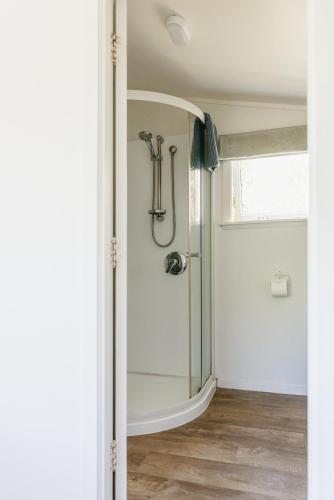 a shower with a glass door in a bathroom at Haumoana Herb Cottage in Haumoana