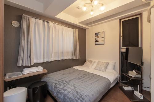 a small bedroom with a bed and a window at Impulse Imazato in Osaka