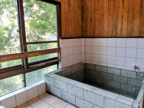 a bathroom with a bath tub in front of a window at 熱海温泉自然郷の眺望の貸し切り in Atami