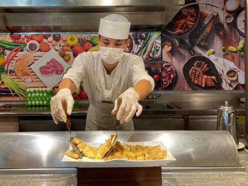 a chef in a kitchen preparing a plate of food at Howard Beach Resort Kenting in Kenting