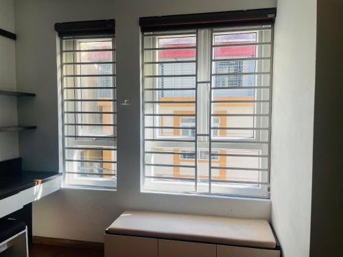 two windows in a room with a bench in front at Laca Home in Hanoi