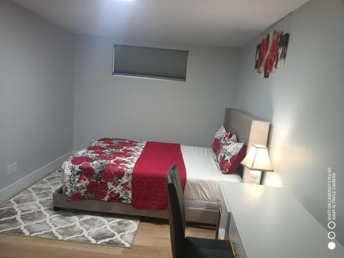a bedroom with a bed with a red blanket and a desk at Live-more cozy newly built one-bedroom apartment in Moncton