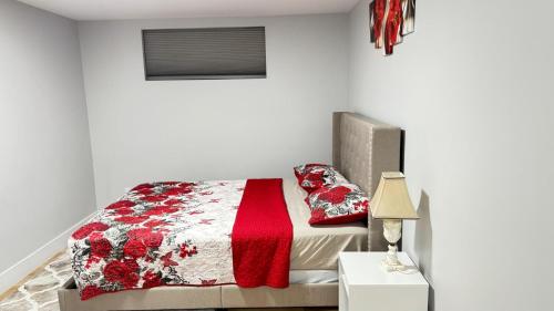 a bedroom with a bed with a red and white quilt at Live-more cozy newly built one-bedroom apartment in Moncton