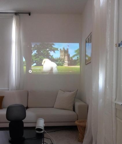 a living room with a couch and a tv on the wall at Appartement et jardin près du lac in Nidau