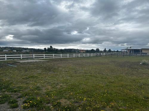a white fence in a field next to a field at Cabañas quilquico spa in Quilquico
