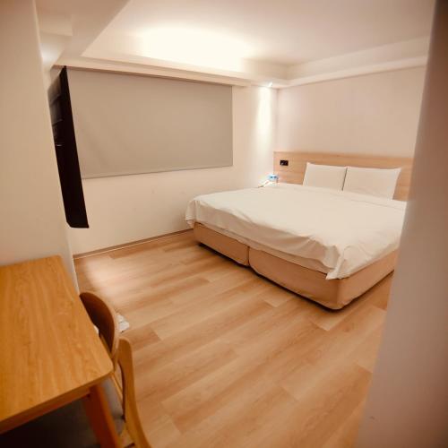 a bedroom with a white bed and a wooden floor at Fooyee Hotel - Yonghe in Yonghe