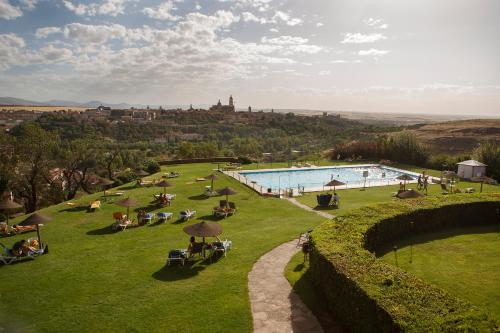 uma piscina num campo com pessoas sentadas à sua volta em Parador de Segovia na Segóvia