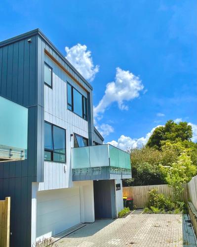 a contemporary house with a glass facade at Valley Sea View Villa Torbay in Auckland