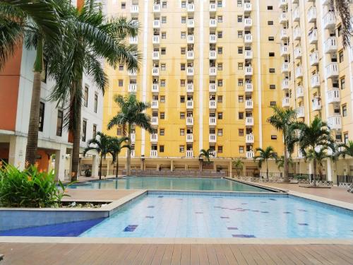 a swimming pool in front of a large building at Room 88 Kemang View Apartment Tower Flamboyant in Pekayon Satu