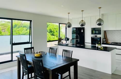 a kitchen with a wooden table and chairs in a room at Valley Sea View Villa Torbay in Auckland