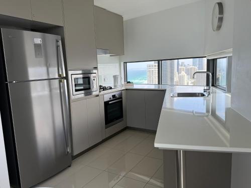 a kitchen with a stainless steel refrigerator and white cabinets at Rhapsody Resort - Official in Gold Coast