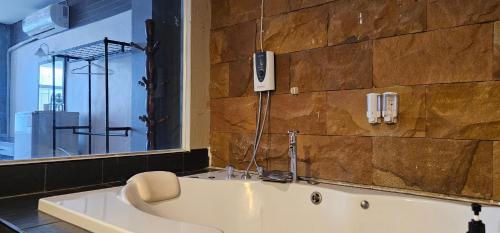 a bathroom with a bath tub with a phone on the wall at Velanon Phuket in Ban Lo Long