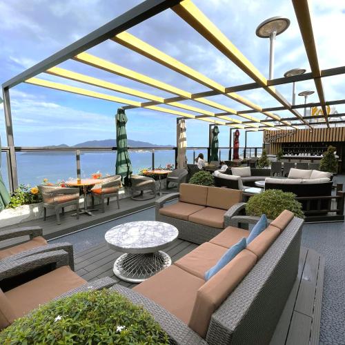 a patio with couches and tables and a view of the ocean at Queen Ann Nha Trang Hotel in Nha Trang